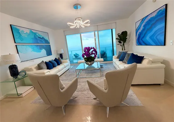 a living room with furniture a fireplace and a chandelier