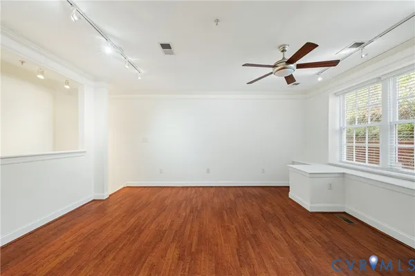 an empty room with wooden floor and windows