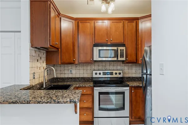 a kitchen with granite countertop a stove sink and microwave