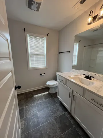 a bathroom with a granite countertop sink a toilet and shower