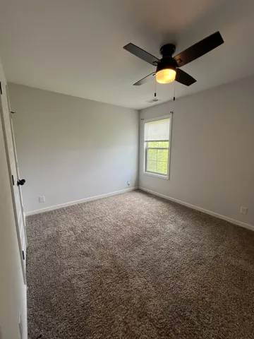 an empty room with a ceiling fan and a window