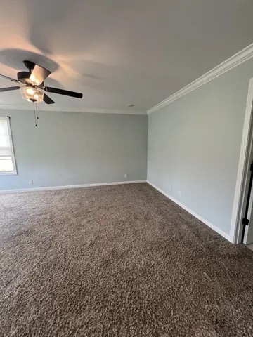 an empty room with ceiling fan and window