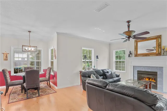 a living room with furniture a fireplace and a dining table with wooden floor