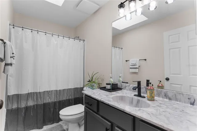 a bathroom with a granite countertop sink a toilet a mirror and shower curtain