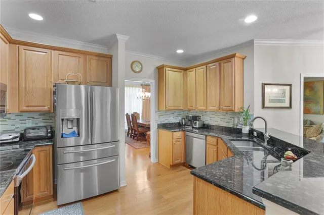 a kitchen with stainless steel appliances granite countertop a refrigerator a sink a stove and island