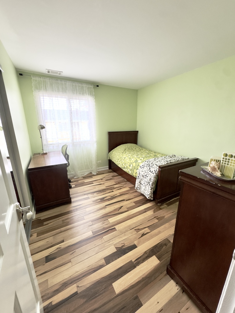 7210 Adams Street, Unit D Willowbrook, IL 60527 - Photo 16 of 19 a bedroom with a bed and wooden floor