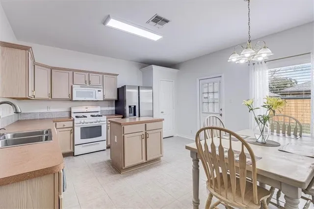 a kitchen with stainless steel appliances kitchen island granite countertop a stove a sink dishwasher a refrigerator with a dining table and chairs