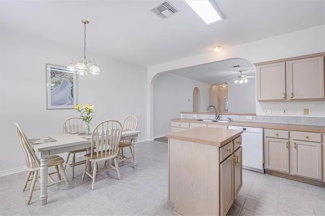 a kitchen with kitchen island granite countertop a sink a stove a dining table and chairs