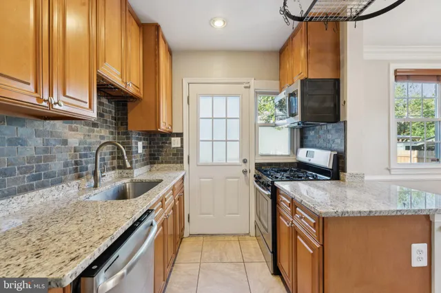 a kitchen with granite countertop stainless steel appliances a sink stove and cabinets