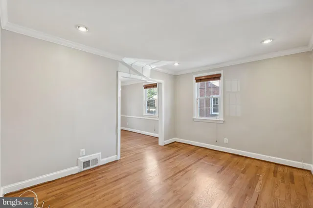 an empty room with wooden floor and windows