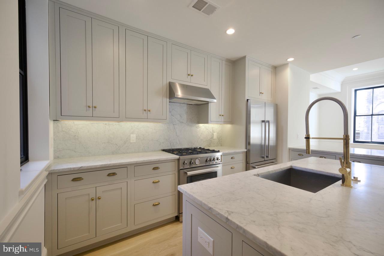 1227 North 6th Street Philadelphia, PA 19122 - Photo 12 of 32 a kitchen with white cabinets and stainless steel appliances