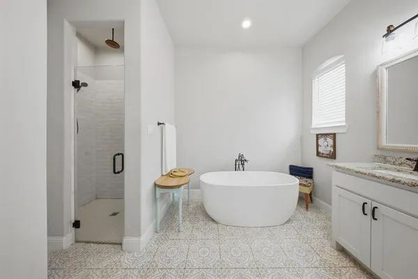 a spacious bathroom with a tub sink and mirror