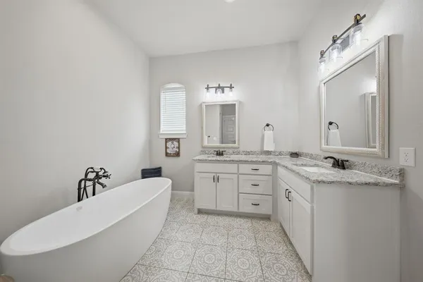 a spacious bathroom with a granite countertop sink a mirror and bathtub