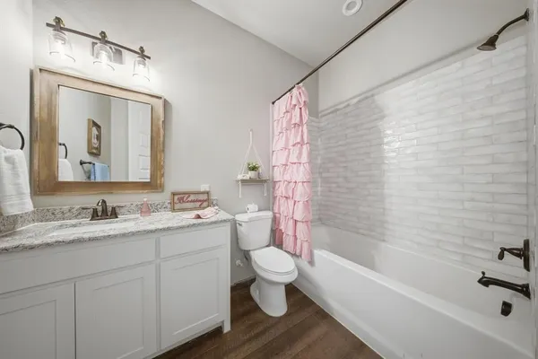 a bathroom with a toilet a sink a tub and a mirror