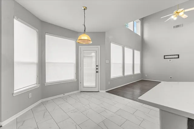 a view of an empty room with window and chandelier fan