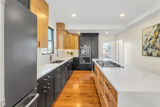 a large kitchen with stainless steel appliances a sink and a wooden floor
