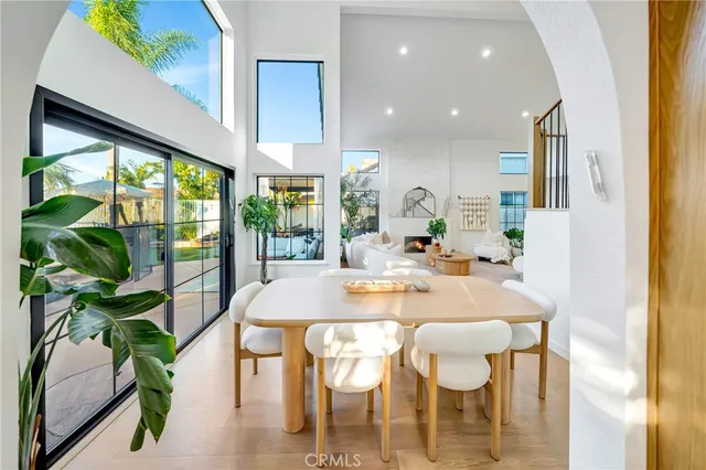 a dining room with furniture a potted plant and a floor to ceiling window