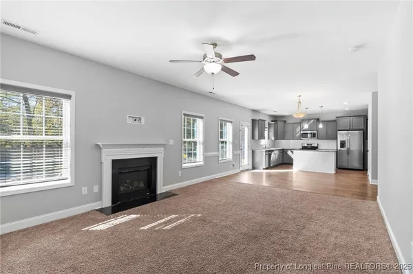 a view of a kitchen with a stove cabinets a fireplace and a ceiling fan