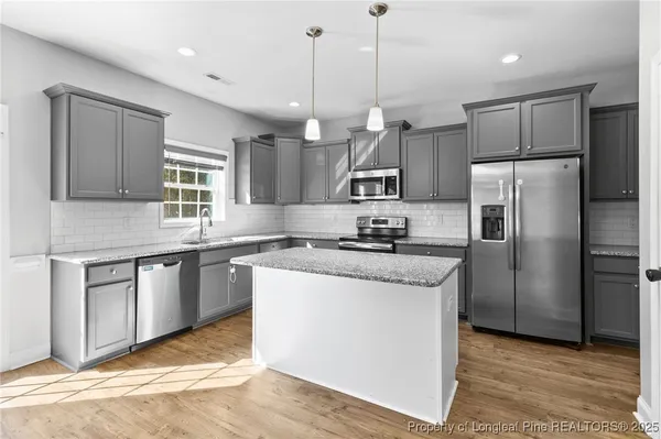 a kitchen with stainless steel appliances granite countertop a refrigerator a sink a stove a microwave and wooden cabinets