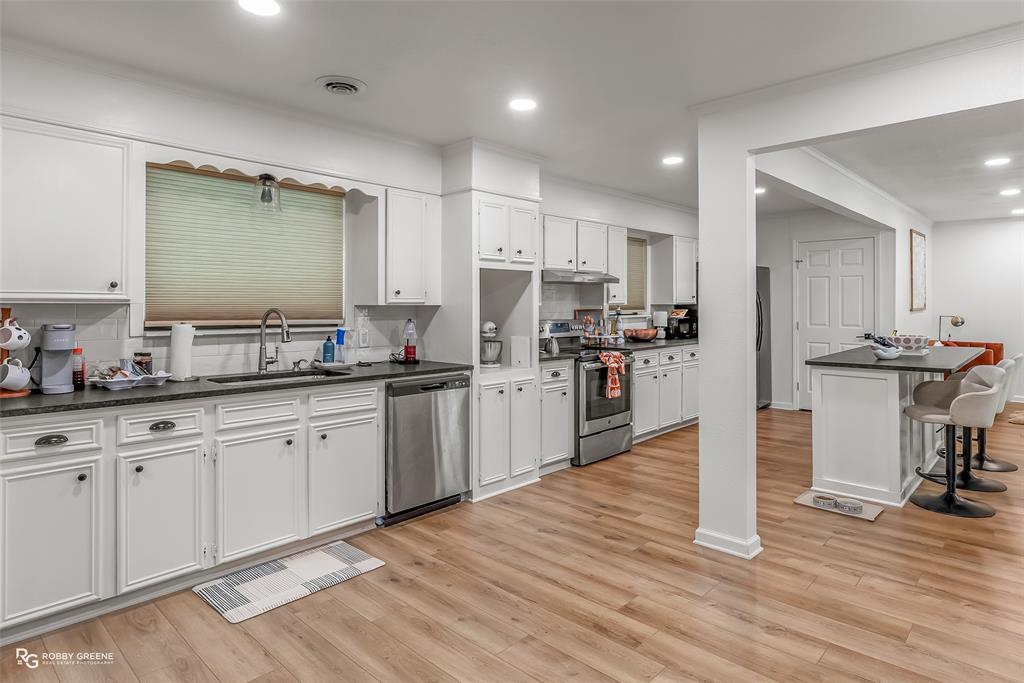 146 Bolinger Hill Road Plain Dealing, LA 71064 - Photo 10 of 32 a kitchen with granite countertop a refrigerator oven a sink white cabinets and wooden floor