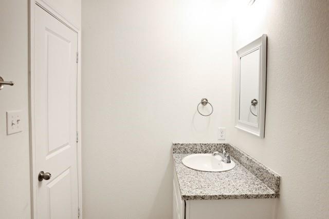 802 South 5th Street, Unit 1 Bonham, TX 75418 - Photo 19 of 25 Bathroom vanity featuring a speckled countertop, integrated sink, and chrome fixtures