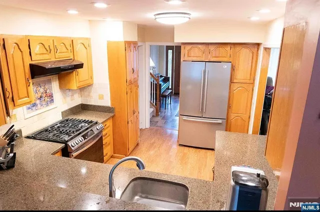 a kitchen with stainless steel appliances granite countertop a refrigerator and a stove top oven