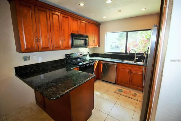 a kitchen with stainless steel appliances granite countertop a stove a sink and a microwave