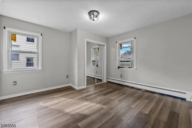 a view of an empty room with window and wooden floor