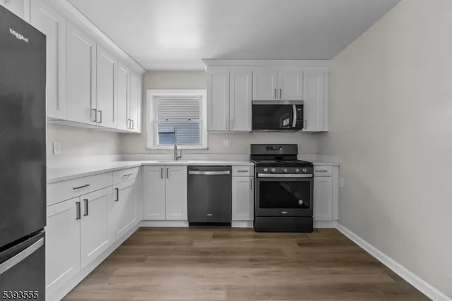 a kitchen with cabinets stainless steel appliances and wooden floor