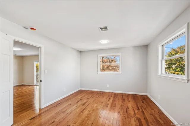a view of empty room with wooden floor and window