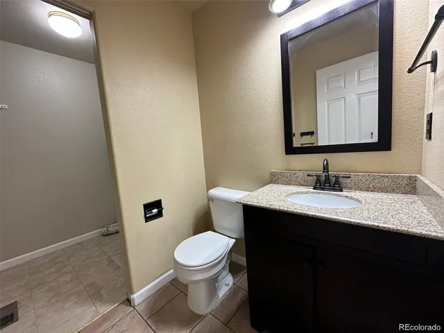 a bathroom with a granite countertop sink toilet and mirror