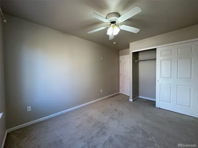 an empty room with a chandelier fan and closet