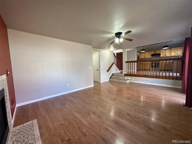 a view of a livingroom with wooden floor a ceiling fan and staircase