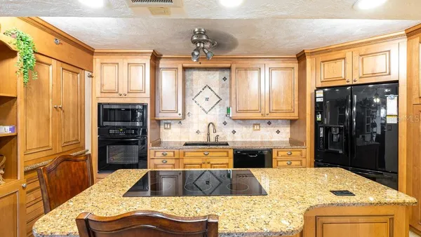 a large kitchen with stainless steel appliances granite countertop a refrigerator and a stove top oven