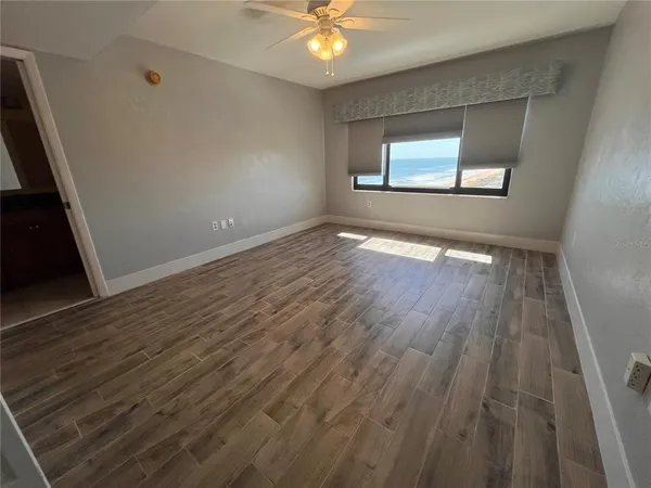 a view of an empty room with wooden floor and a window