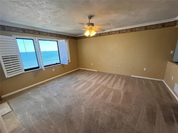 an empty room with windows and ceiling fan