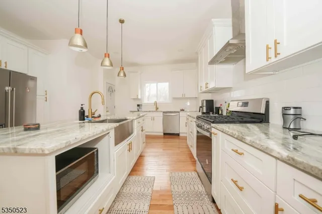 a kitchen with stainless steel appliances granite countertop a sink a stove and a wooden floors
