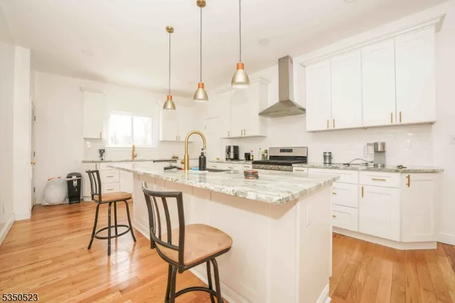a kitchen with stainless steel appliances white cabinets a sink and a stove