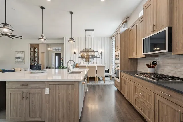 a kitchen with kitchen island granite countertop a stove a sink and a wooden floors