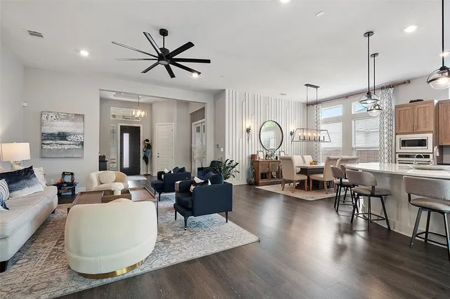 a living room with furniture kitchen view and a wooden floor