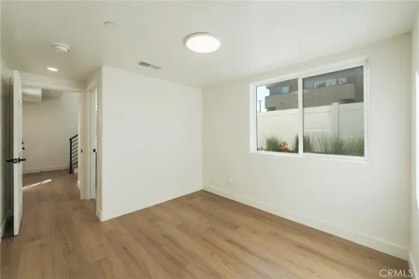 a view of a hallway with wooden floor and a bathroom