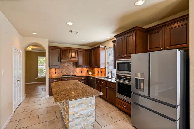 a kitchen with granite countertop a refrigerator and a stove top oven