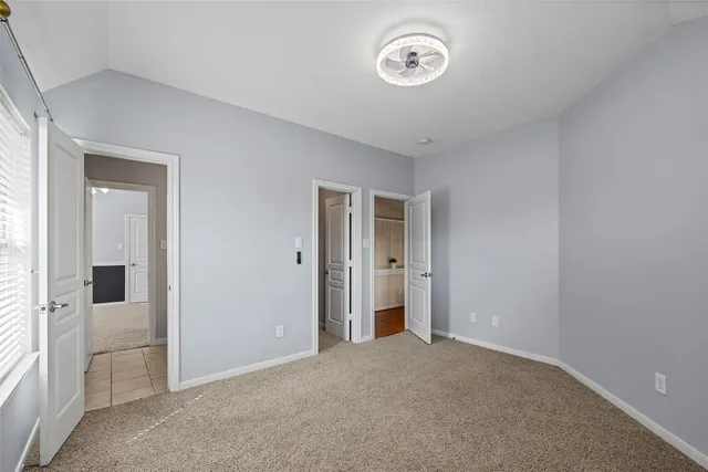 an empty room with chandelier fan and windows
