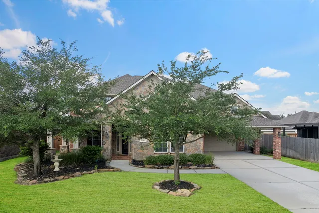 a front view of a house with garden and trees