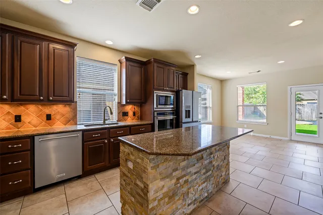 a kitchen with stainless steel appliances granite countertop a sink stove and refrigerator
