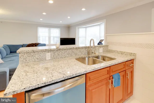 a kitchen with stainless steel appliances granite countertop a sink a stove and a wooden cabinets