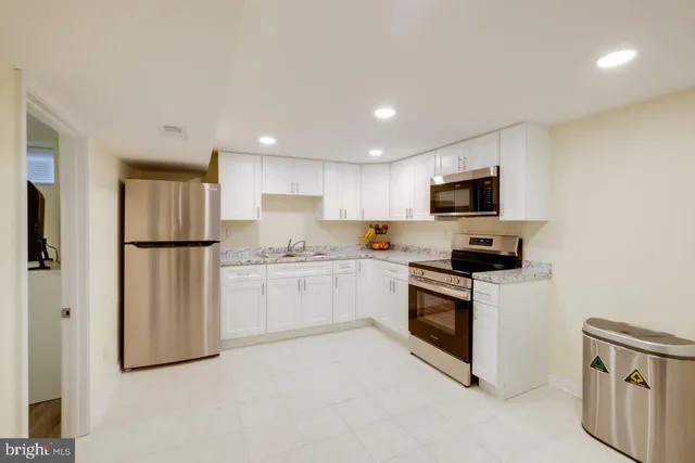 a kitchen with white cabinets stainless steel appliances and a refrigerator