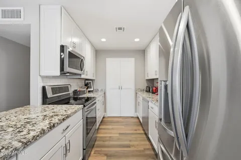 a kitchen with stainless steel appliances granite countertop a refrigerator and a stove