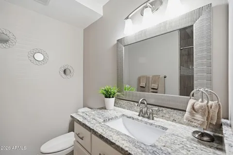 a bathroom with a granite countertop toilet sink and mirror