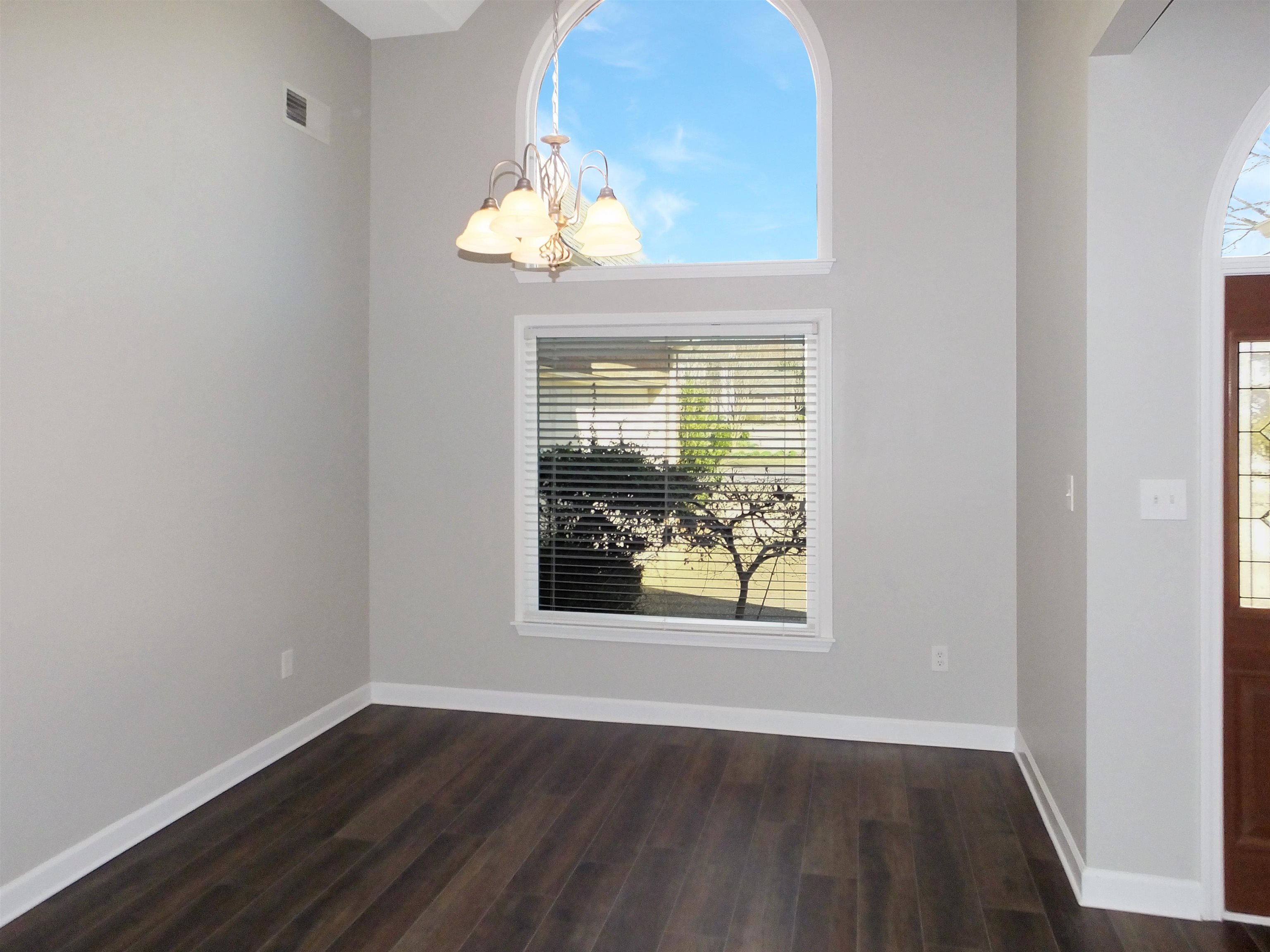 4323 Country Bridge Road Lakeland, TN 38002 - Photo 11 of 35 Spare room featuring an inviting chandelier, baseboards, visible vents, and dark wood-style flooring